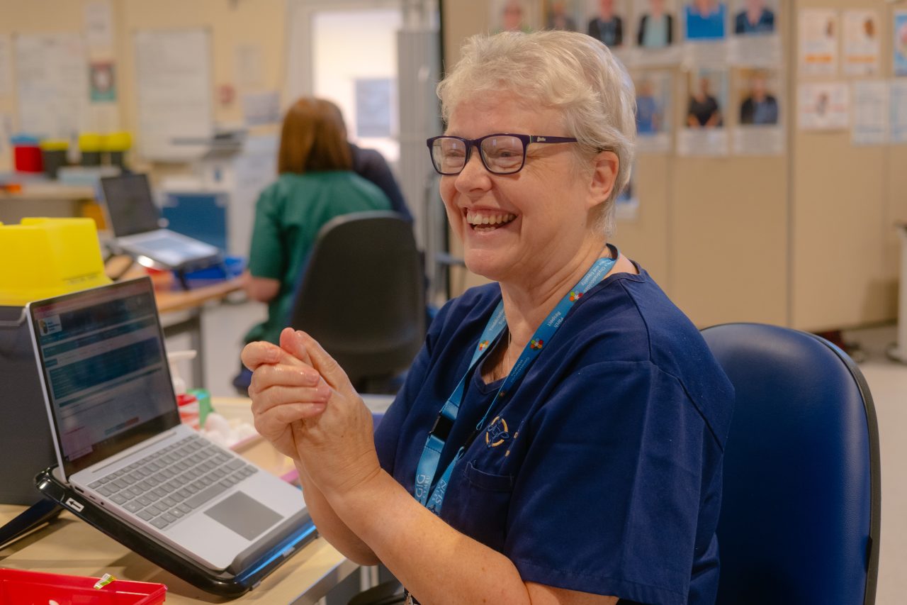 Powys Teaching Health board Staff member in Clinical Setting with laptop.